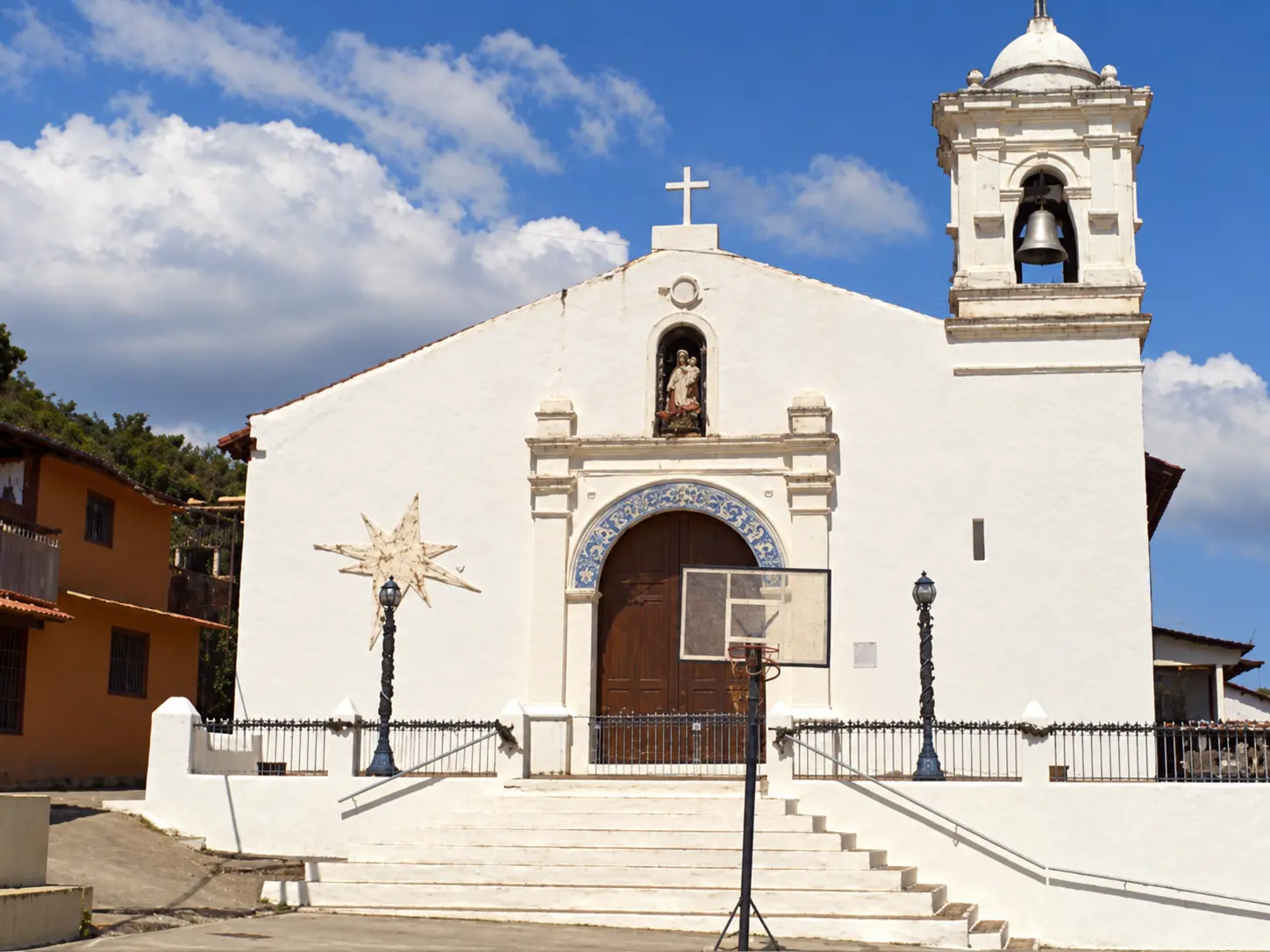 Fachada blanca de la iglesia de San Pedro con su torre campanario y la escalinata de acceso